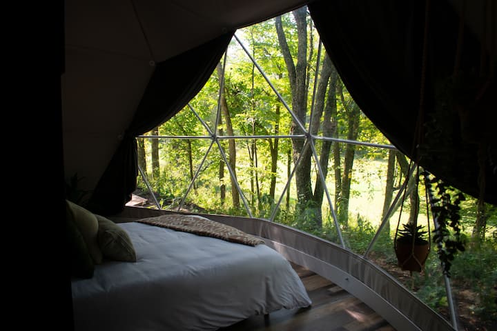 Lower queen bed and panoramic window overlooking the forest—large curtains can be pulled over entire window for complete privacy.