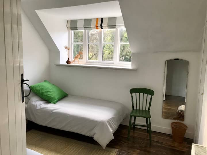 The bedroom with two single beds is simply but comfortably furnished and overlooks trees at the back of the house.
