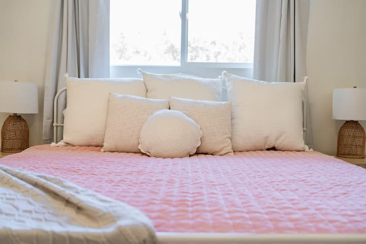 Angalia maelezo ya hila: taa za rattan kwenye meza za kando ya kitanda na mito laini, isiyoegemea upande wowote, ikiongeza uzuri wa utulivu, wa kimtindo wa chumba.