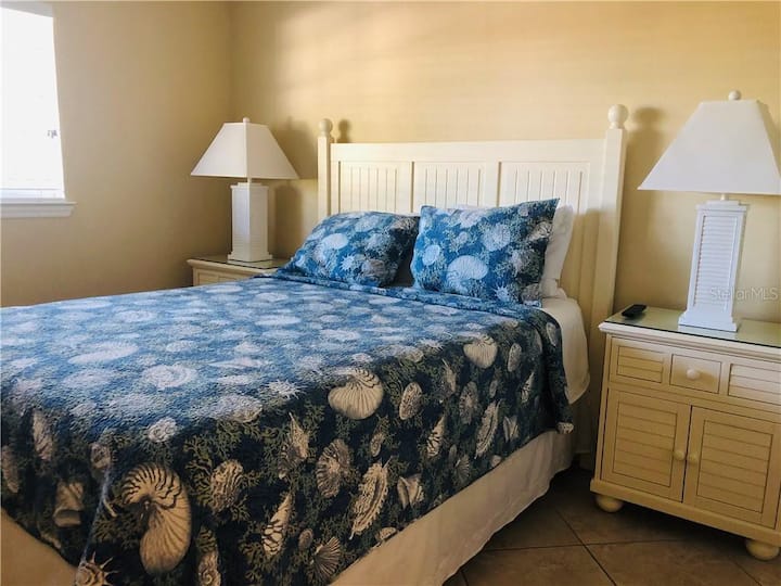 El dormitorio 1 tiene dos mesitas de noche,  vestidor y armario de pared con puerta doble, televisor pequeño con cable y ventilador de techo. El armario de la pared contiene 4 sillas de playa y dos sombrillas de playa para que las uses. También hay almohadas y mantas adicionales en el armario de la pared.