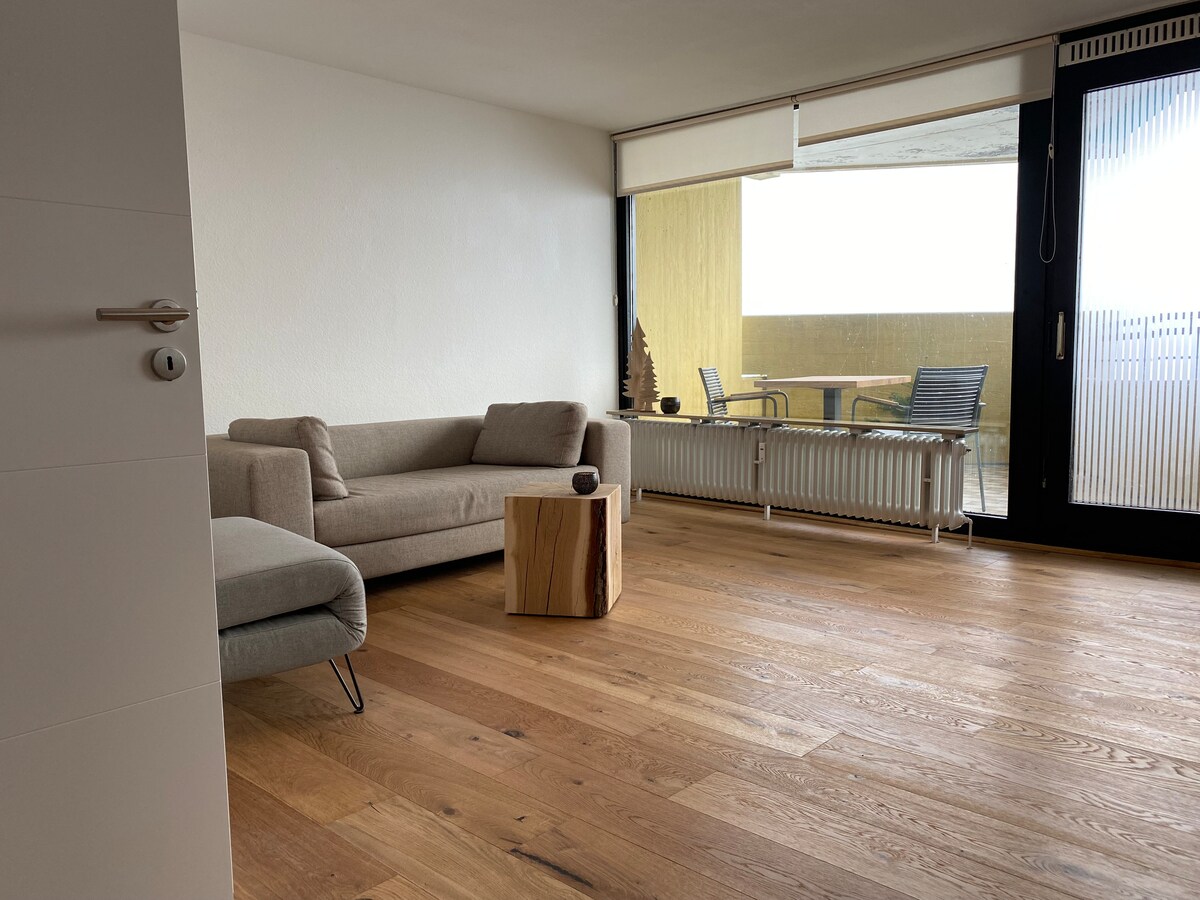 Spacious living room with couch and armchair that can be converted into a third sleeping option. 