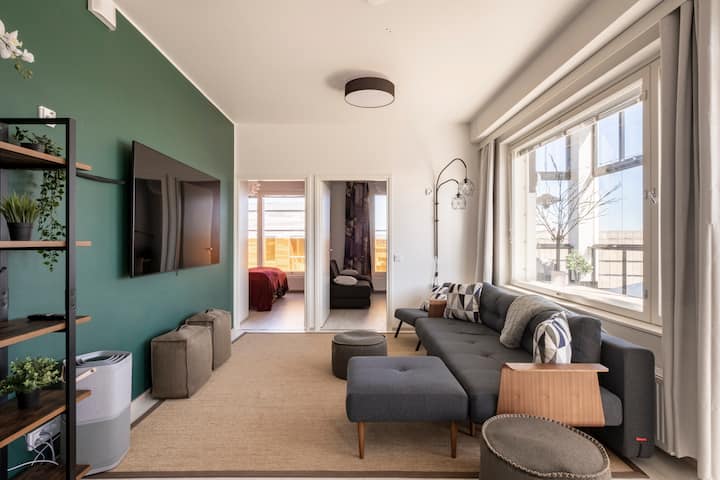 Obývacia izba v štýle salónika má 75-palcový televízor s aplikáciami. Je zariadený škandinávskymi dizajnovými pohovkami a nábytkom. Je to flexibilné pre celú skupinu.