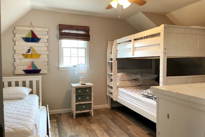 The third floor of this home contains two bedrooms and an ensuite bathroom. This bedroom is to the right when you get to the top of the stairs. It has a full-over-full bunk bed and a twin with twin trundle bed. 