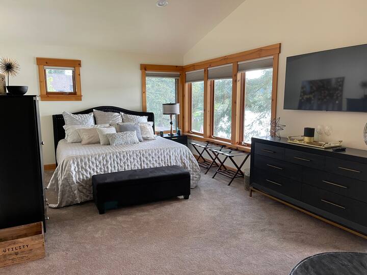 King size bed and dresser/TV in top floor Master Suite with view of lake outside the windows.