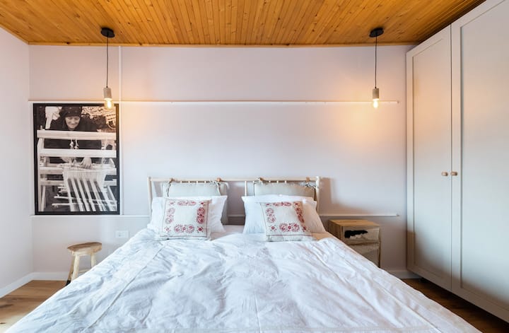 Bedroom with queen size bed dressed in premium linens, rustic pillows that are very soft, clothing storage to organize your belongings, dedicated workspace and access to the first floor terrace where you can enjoy an amazing view of Predelut village