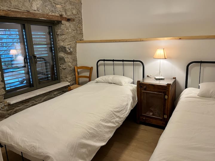 Bedroom with two single beds. The stone wall keeps the room cool in the summer and warm in the winter