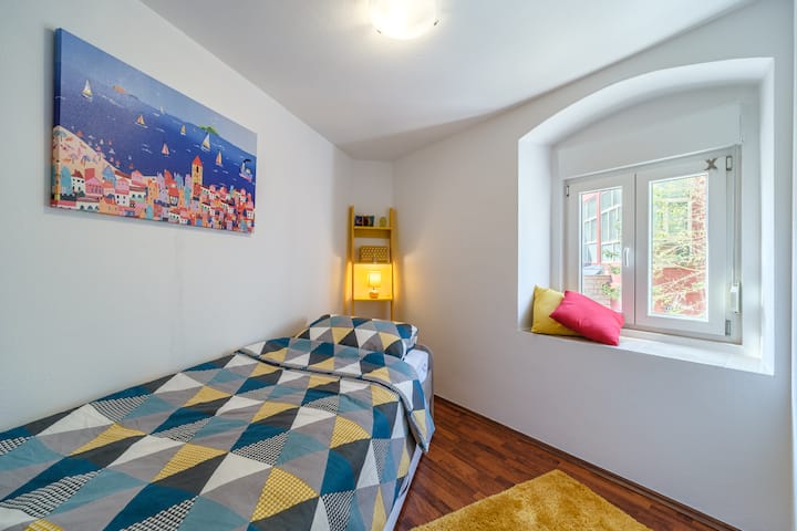 يمكن أن تستوعب هذه الغرفة اللطيفة ذات الإطلالة على الزقاق: طفلان أو شخص بالغ + طفل واحد (لا يمكن أن يدعم سرير الدرج السفلي وزنًا أكبر من 50 كجم!).