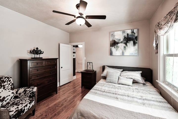 Primaire slaapkamer heeft queensize bed, dressoirs en cowhide printstoel. 