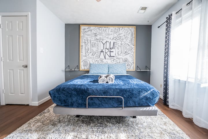 Bedroom 2, queen bed with statement artwork and warm natural light, comfortable retreat with mounted TV and ceiling fan.