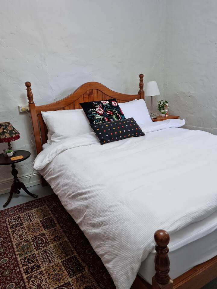 The queen bed in the main bedroom. The walls surrounding are bowed and bumpy but solid!