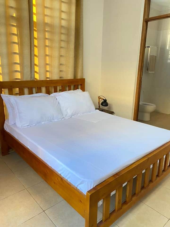 Dormitorio principal con un gran cama doble (5x6 pies) y baño completo adjunto, armario y ventilador de techo. A medida que el aire acondicionado te enfría, las mantas de estilo Masai están disponibles para mantenerte cómodo.