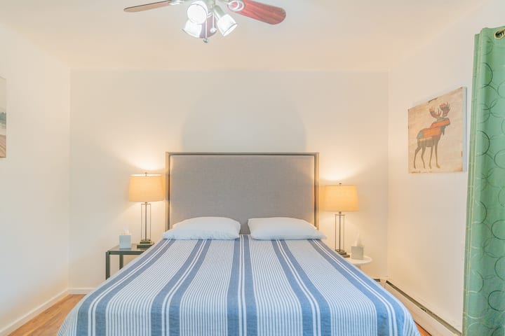 ห้องนอนแรกพร้อมเตียงควีนไซส์และโคมไฟ