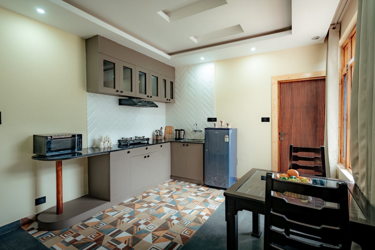A well-equipped kitchen space features modern cabinetry and a sleek countertop. Included are essential appliances such as a stove, microwave, and refrigerator. The dining area is marked by a small table surrounded by four chairs, allowing for casual meals. An attractive tile design enhances the floor's aesthetic.