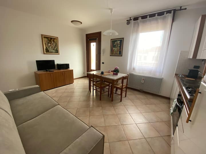 Eneo la kuishi lenye mwanga na starehe lenye sofa, meza kuu ya kulia, eneo la TV lenye oveni ya microwave na jiko lenye vifaa kamili.