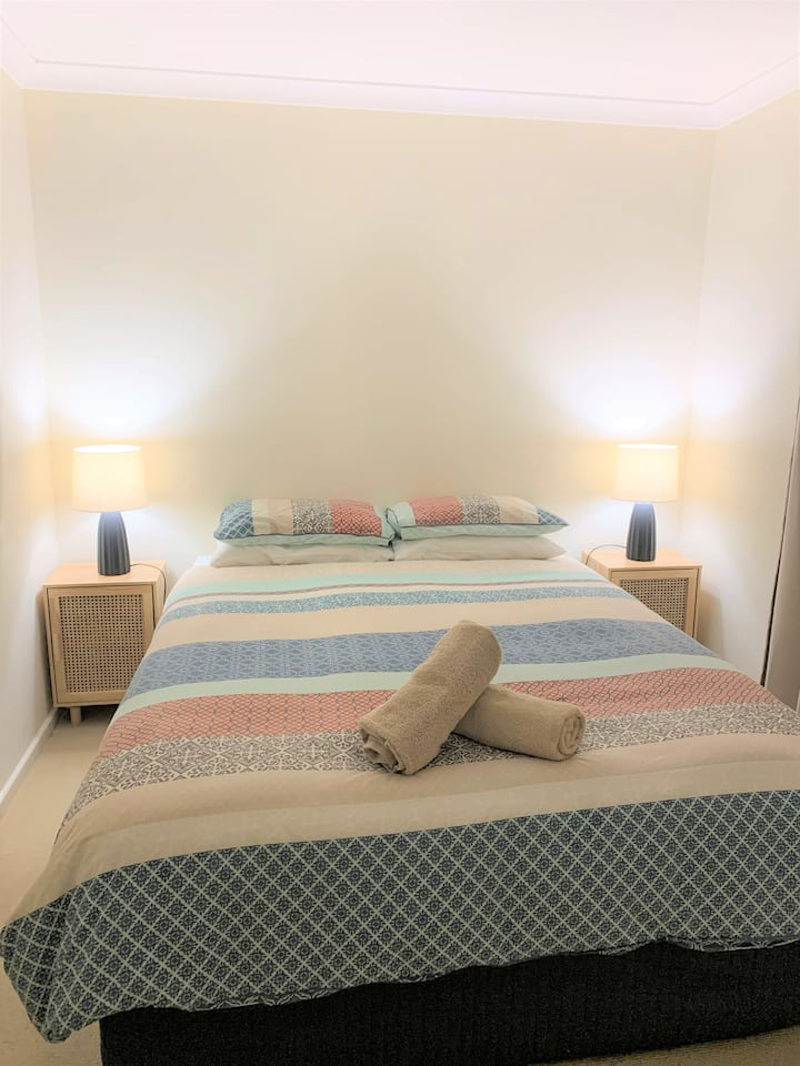 Dormitorio tamaño queen: cama cómoda tamaño queen, doonas, ropa de cama, almohadas y fundas, mesitas de noche/lámparas, armario doble (colgante y estante), aire acondicionado evitativo de ductos, TV, DVD, toallas de baño, alfombras de repuesto en el vestidor