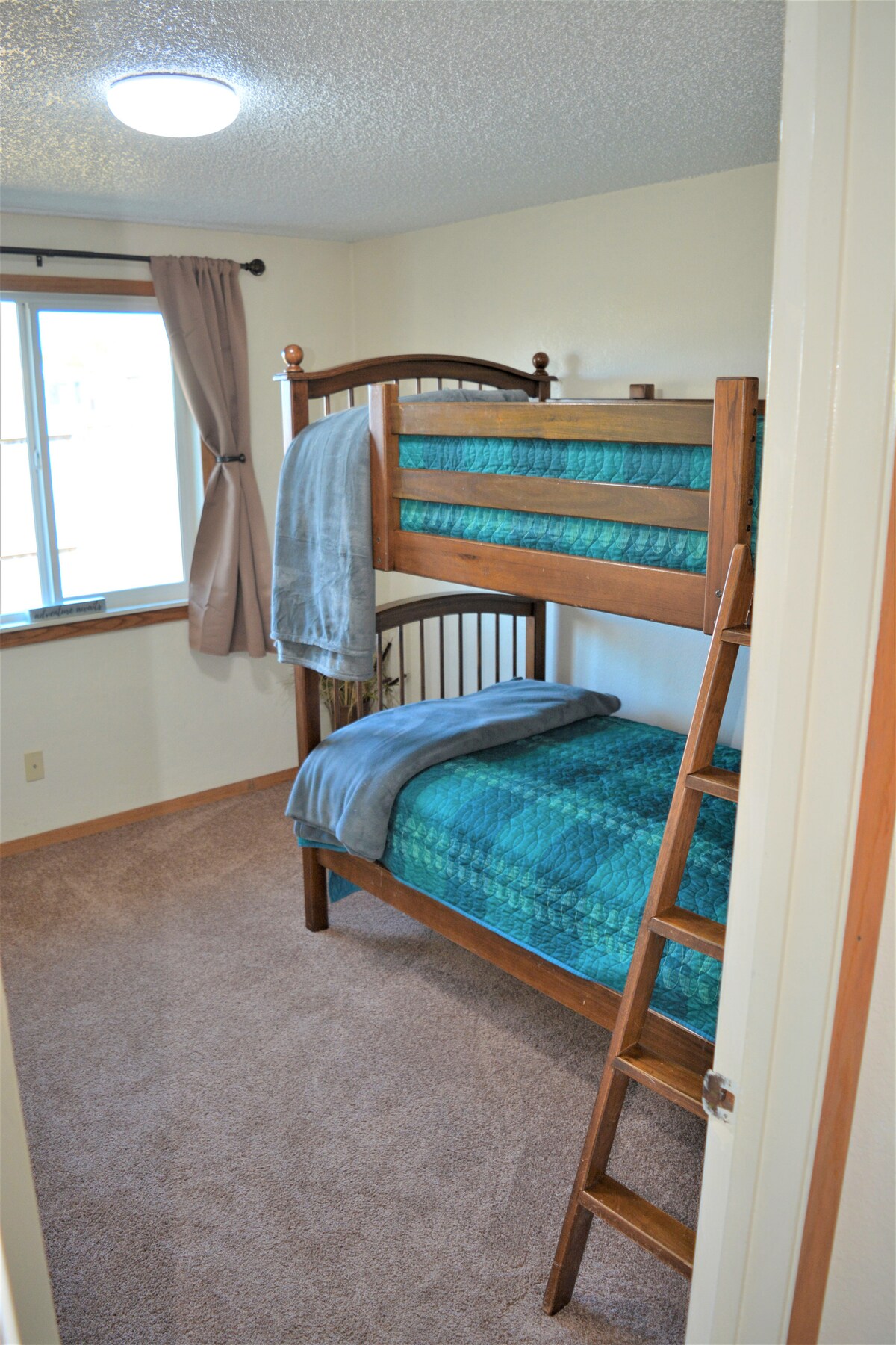 Спалня за гости с уютни двуетажни легла, закачалки за дрехи и багажник.