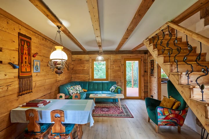 Sala de estar. Atmosférico, docenas de deles de madera de años de antigüedad y lámparas elegantes. Conjunto de salón cómodo después de desplegarse con dos áreas para dormir. Muebles de madera, una cómoda silla bajo las escaleras y decoraciones folclóricas. Salida directa al patio. 