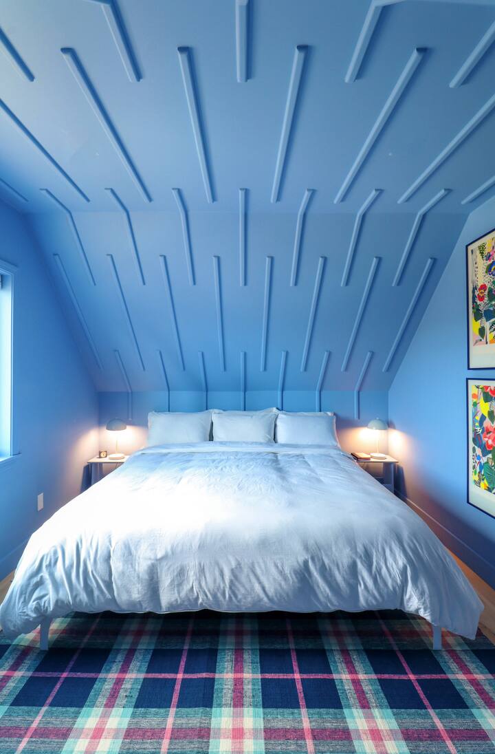 Blue room with a king bed, modern art and bespoke trim