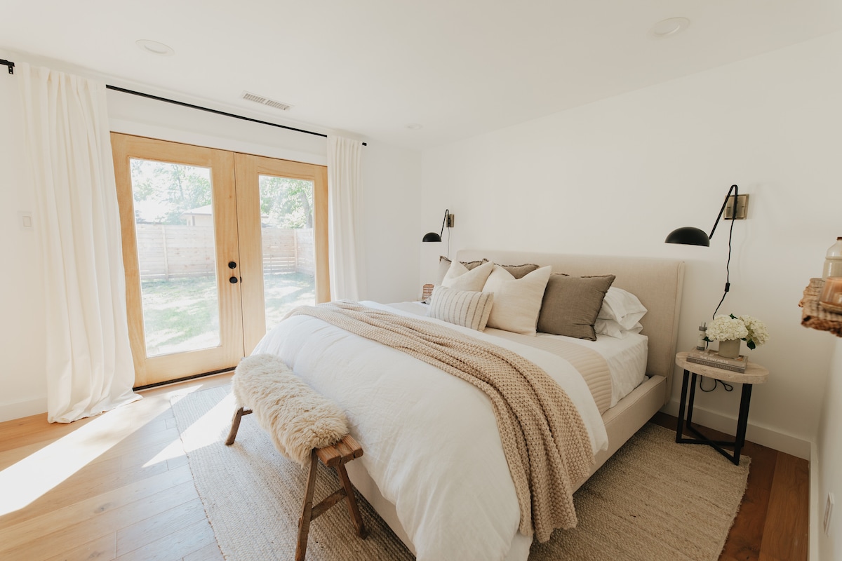 ¡Disfruta de una exuberante cama tamaño king, con un edredón 100% solo para ropa de cama mejorada por el spray de ropa de cama y la cálida luz de la mañana que entra por las puertas francesas!