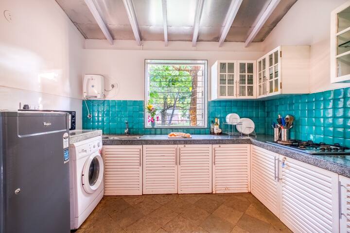 Fully equipped kitchen with appliances, utensils, crockery and a lovely garden view.