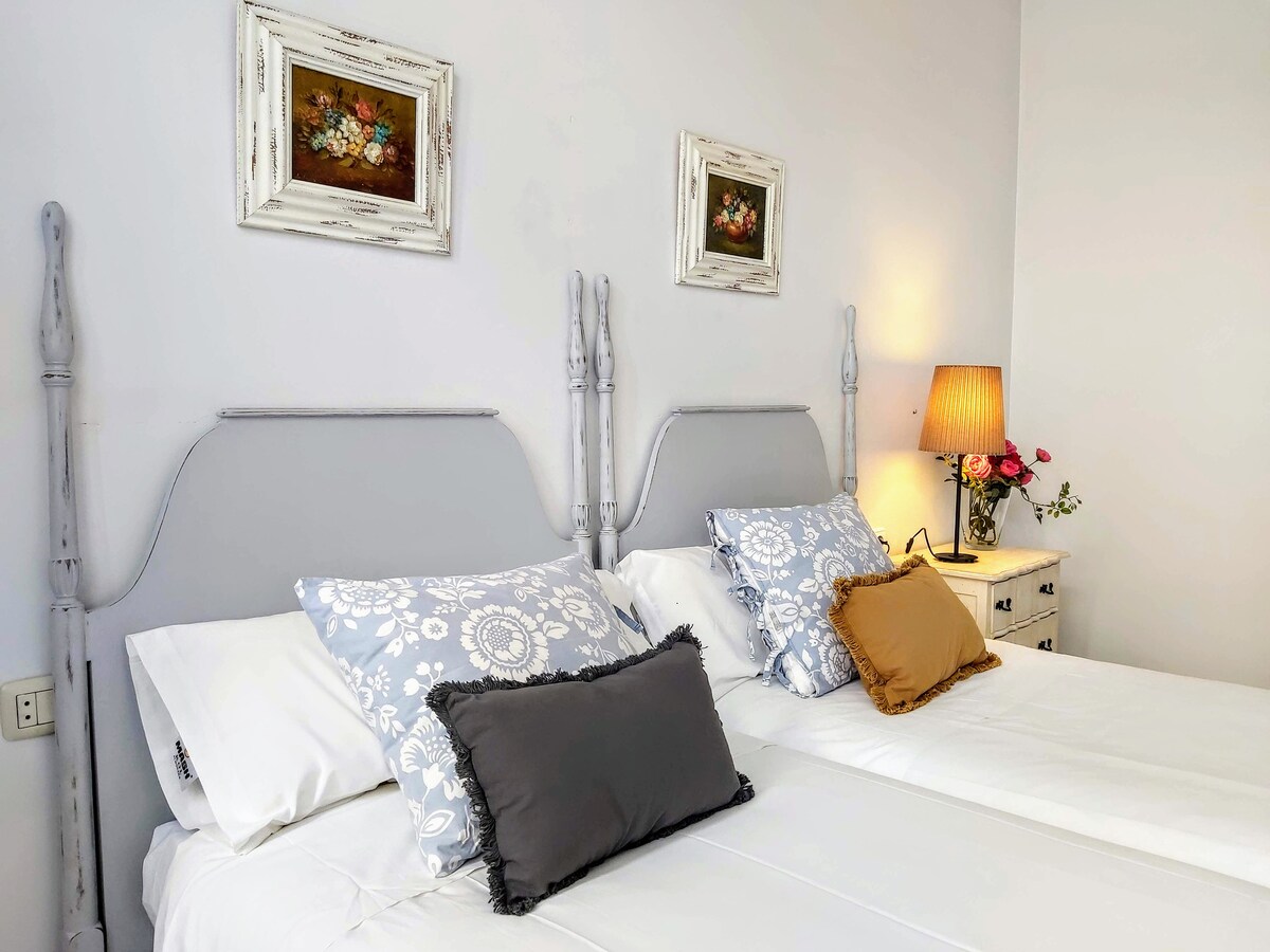 Ოთახი კლასიკური ხიბლით, სადაც ბუნებრივი სინათლე ეფერება ყველა კუთხეს. Რბილი ტონები, ყვავილების დეტალები და მისი დეკორაციის სითბო ქმნის მყუდრო გარემოს, რომელიც იდეალურია დაბინავების მომენტიდანვე დასვენებისა და შინაურული გარემოს შესაქმნელად.