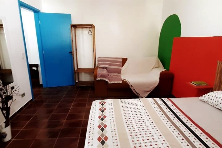 Dormitorio con somier doble y sofá cama, tocador, perchero para acomodar ropa y ventilador de techo.