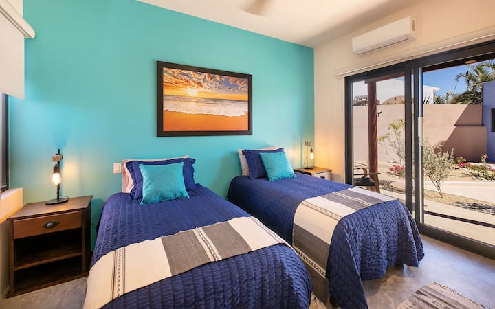 Spavaća soba na katu s dva kreveta pojedinačne veličine, spojenom kupaonicom i terasom.