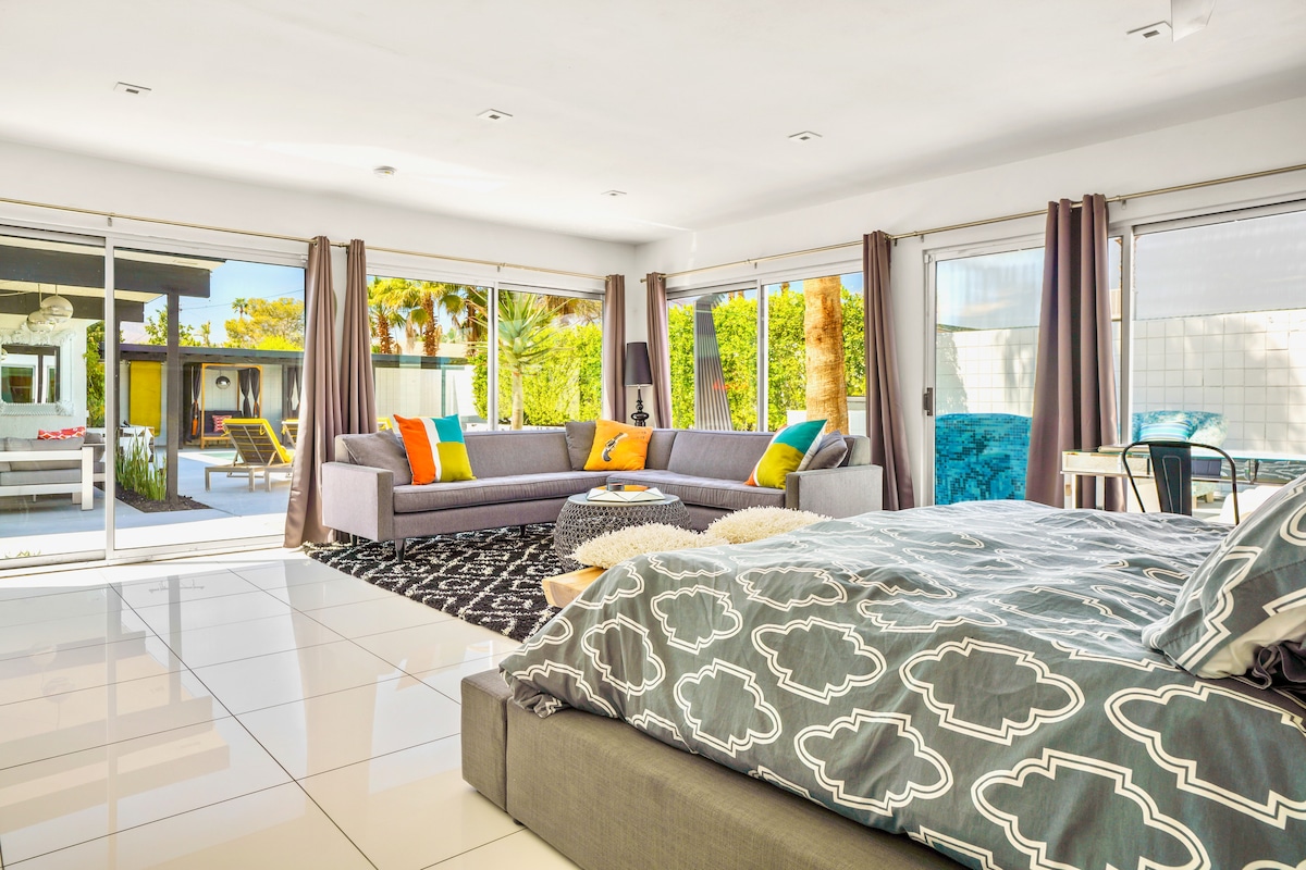 Suite Casita con cama King, gran sofá seccional y 2 paredes de ventanas correderas al patio y a la chimenea.