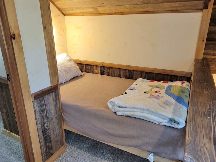 Slaaphoek met twee eenpersoonsbedden op de top van de trap. 