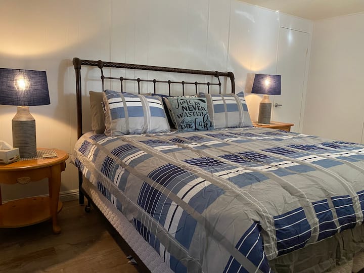 Det største soveværelse har også et skrivebord, en stol og en kommode.  Sengen vender ud mod verandaen (som virkelig er bagsiden af huset).  Fin udsigt over træerne og vasken.