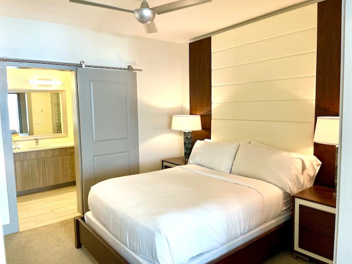 Guest bedroom with queen bed, flatscreen TV, and en suite bathroom with double vanities and walk-in shower