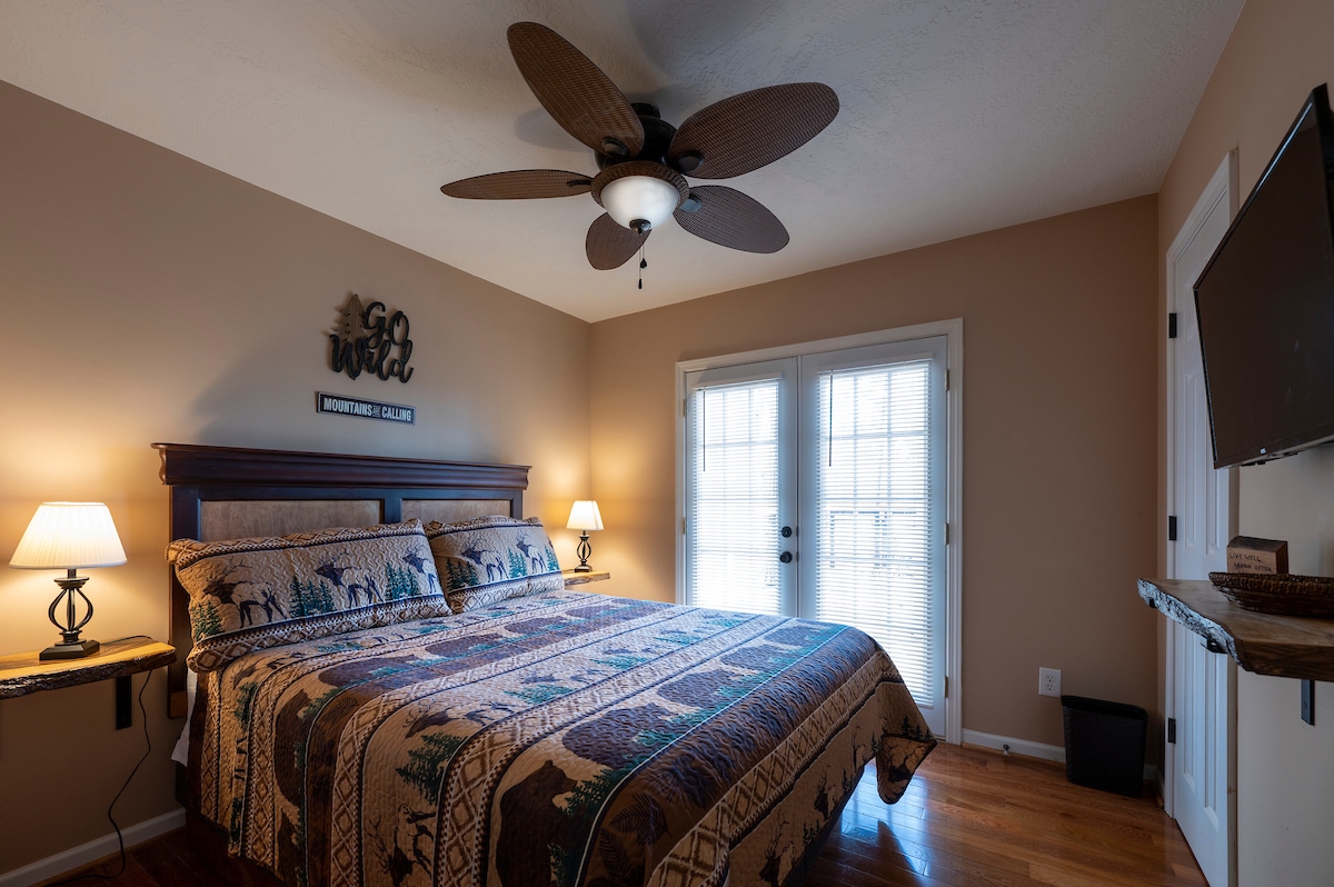 غرفة نوم مع أبواب فرنسية إلى الشرفة الخلفية