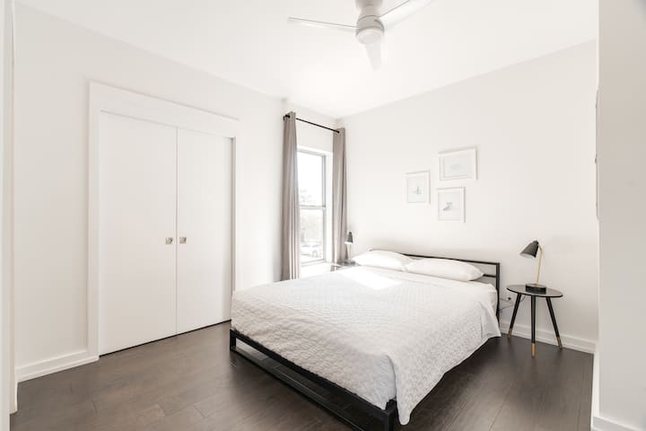 Minimalist bedroom with crisp white bedding, sleek black accents, and soft natural light. A peaceful, modern escape.
