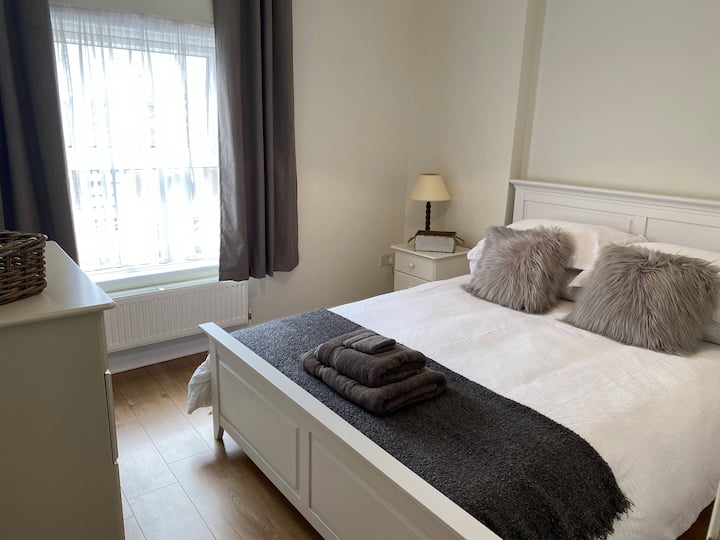 Habitación principal con hermosa ropa de cama fresca, mesita de noche con una lámpara
