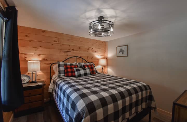 Entra nella camera da letto 2 con un letto queen-size, un ventilatore a soffitto e tende oscuranti.