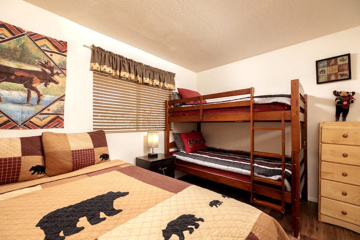 Camera da letto al piano inferiore con letto queen-size, letti a castello singoli e abat-jour con porte usb per una ricarica facile del telefono.