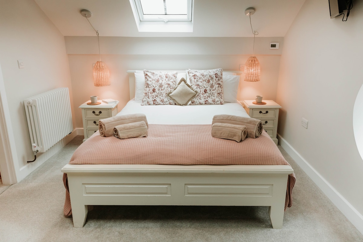 Голямото двойно легло в спалнята с свежо бяло спално бельо и матрак Hypnos, плътно в стрехите...