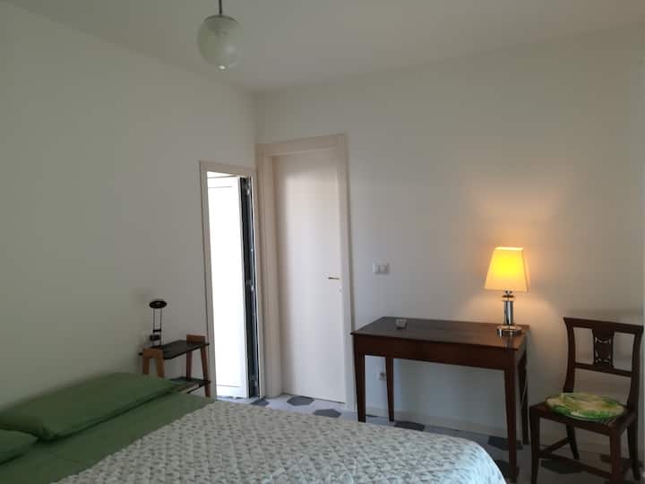 El dormitorio con la cama doble que se puede convertir en dos camas individuales. Tenga en cuenta la puerta abierta que conduce a un balcón y el antiguo escritorio útil para trabajar en paz.