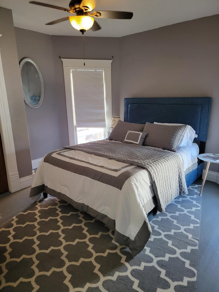 Dormitorio gris con cama tamaño queen