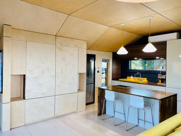 As a modern living space, the main room consists of the kitchen, seating, and kitchen island during the day.  The 370 sq ft space is custom crafted in birch, and packs it all in drawing attention to the view through the wide windowed walls.