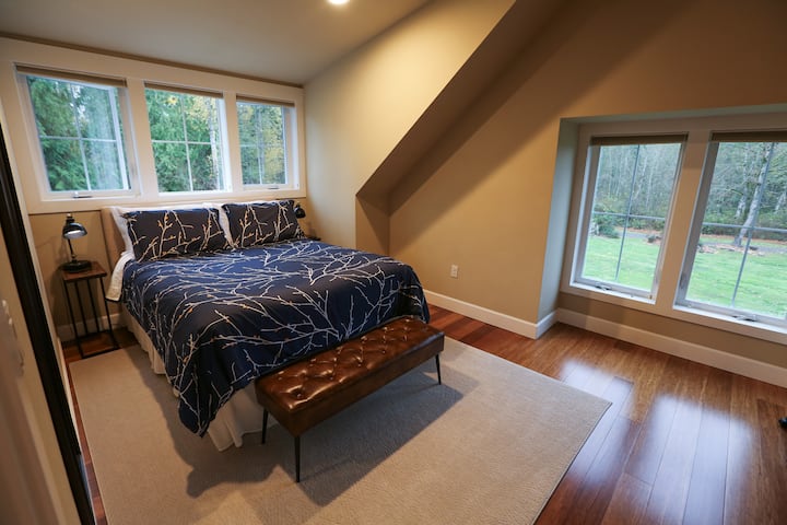 Spavaća soba s bračnim krevetom, komodom i vješalicom.