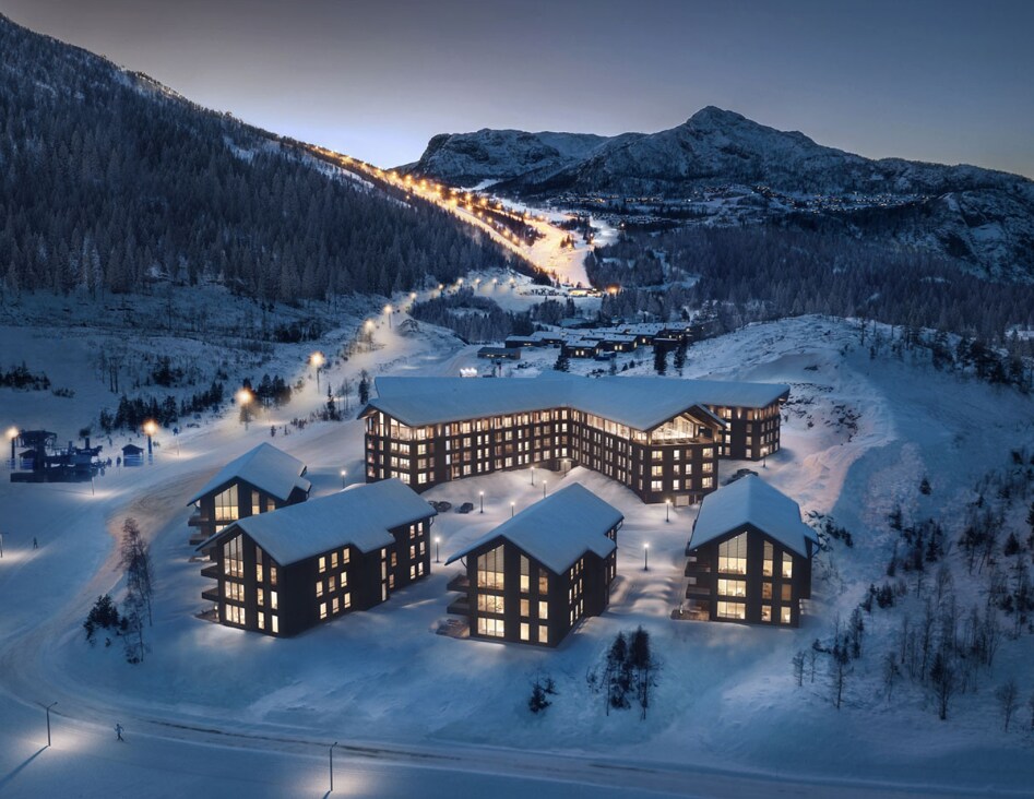 The image presents a snow-covered landscape featuring several modern buildings at twilight. Soft yellow lights illuminate the structures, contrasting against the white snow. Ski slopes are visible in the background, and the serene mountains create a tranquil backdrop.