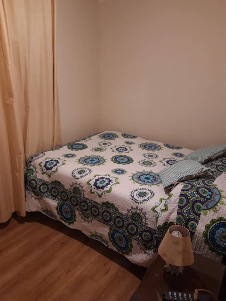 Dormitorio 2 con cama de dos plazas pequeña (tamaño full de 135 cm de ancho y 190 cm de largo), guardaropa y velador.