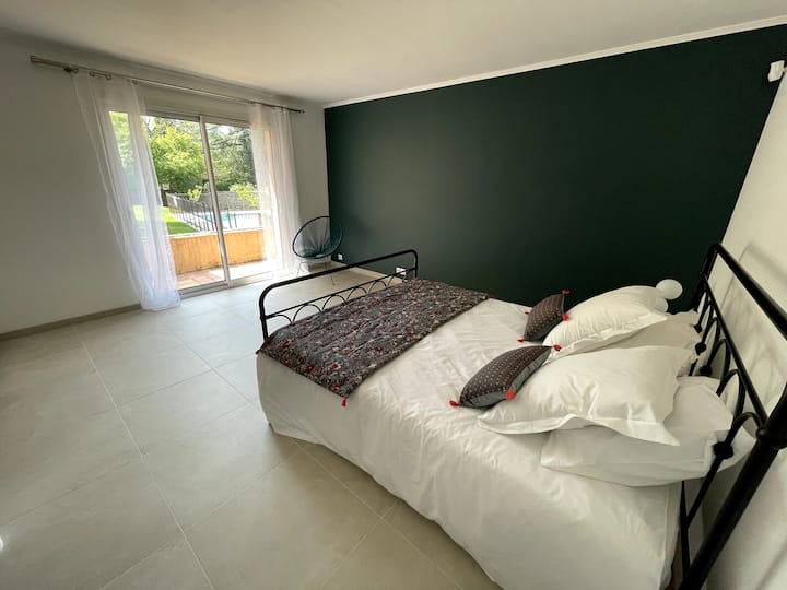 Suite principal en la planta baja con baño privado con inodoro y balcón con vistas al jardín y a la piscina.