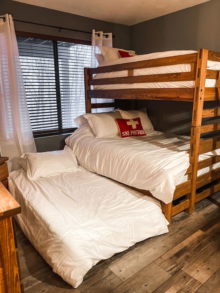 The second bedroom includes a full-sized bed under a twin bunk bed. Additionally, there is a twin-sized trundle pull-out for additional sleeping space. This bedroom has direct access to the second full bathroom.