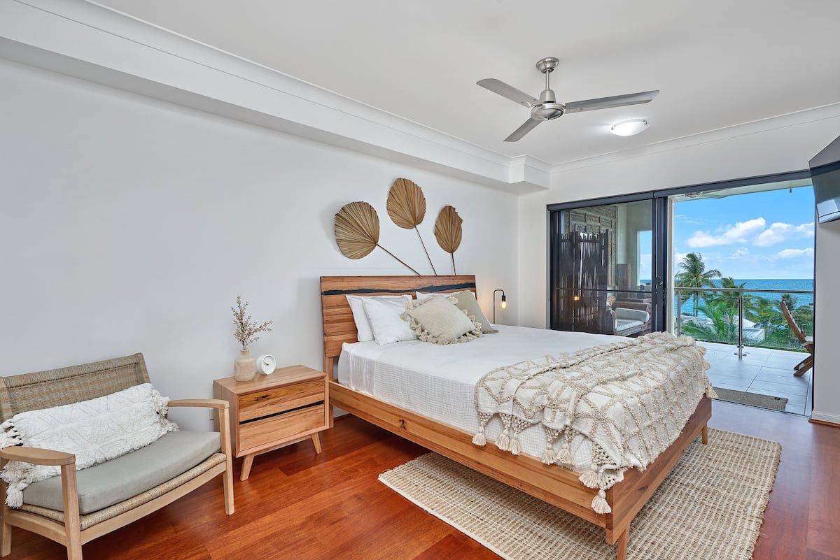 Bedroom with beachside views through the window and balcony of Trinity Beach