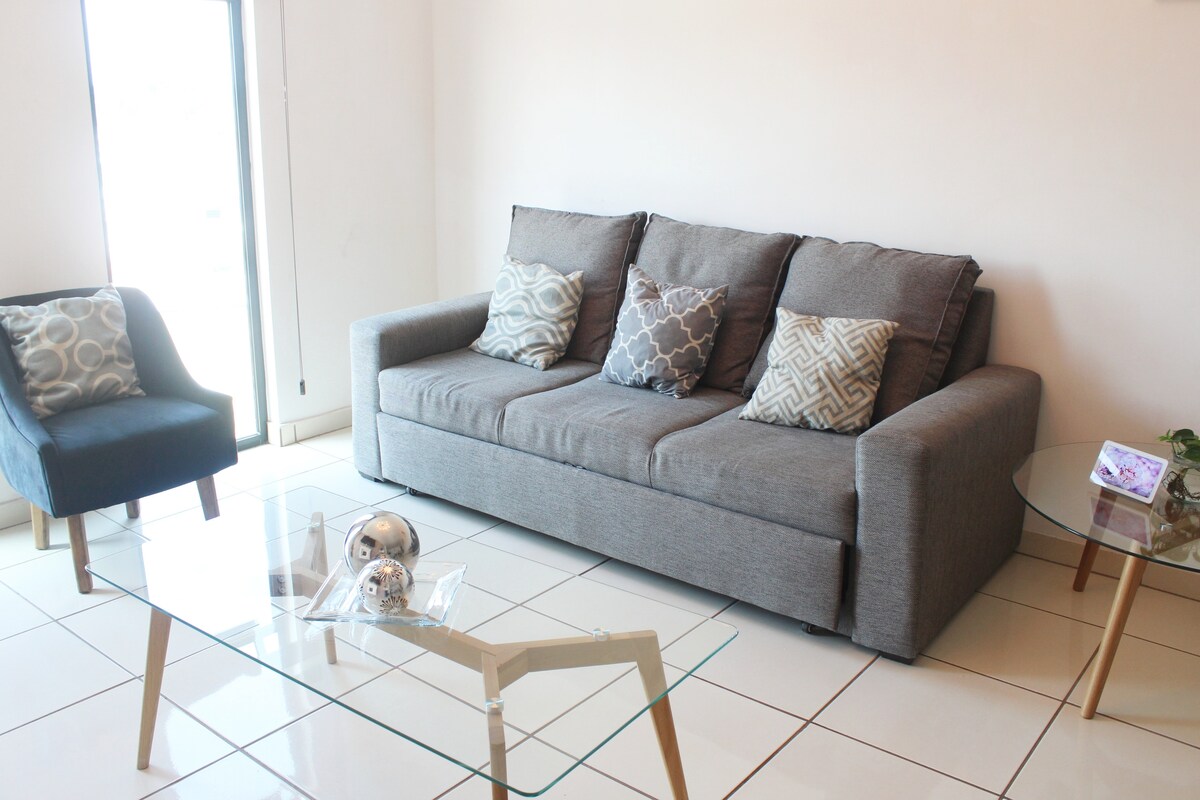 غرفة معيشة بسرير أريكة مريح. 
لدينا شاشة مسطحة ومساعد Google.