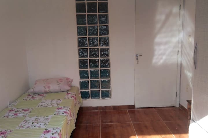 Quarto com bicama, guarda roupas e ventilador.