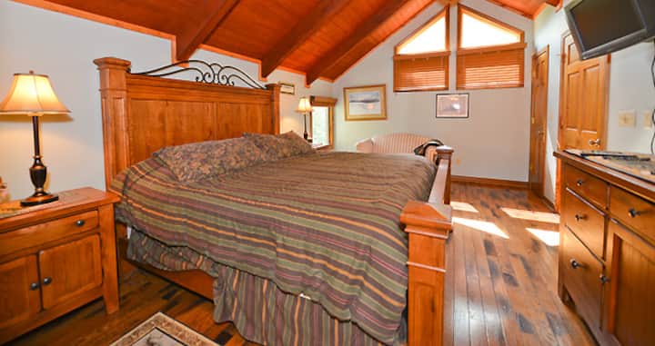 جناح رئيسي كبير في الطابق الثاني مع سرير كينج وحمام داخلي ومروحة سقف وتلفزيون.