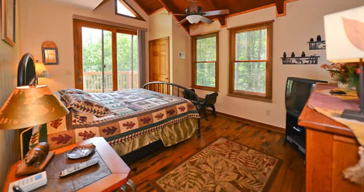 غرفة نوم رئيسية في الطابق الأول بسرير كبير ومروحة سقف وتلفزيون.